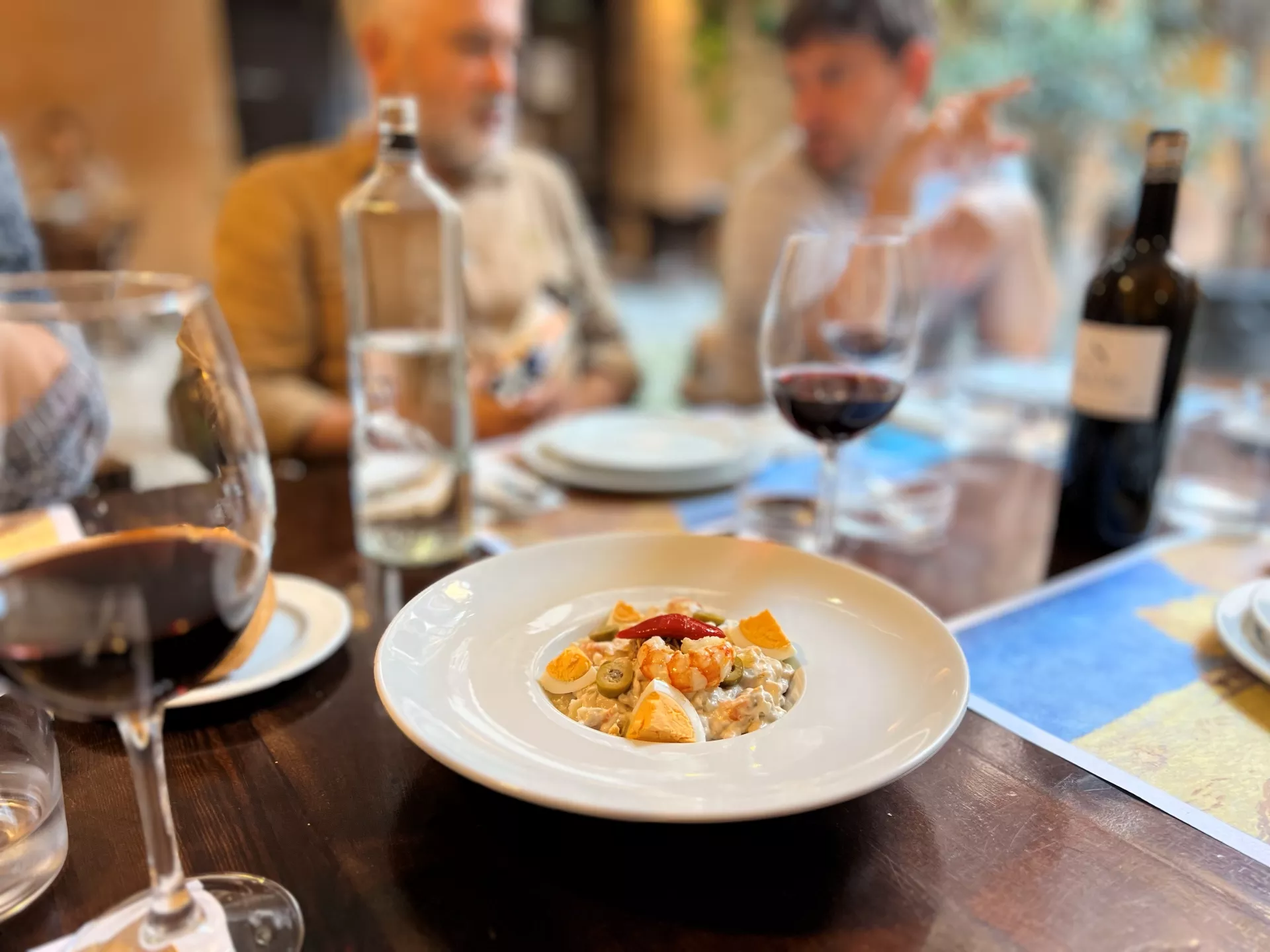 Mesa de restaurante con varios comensales, comida y bebida servida